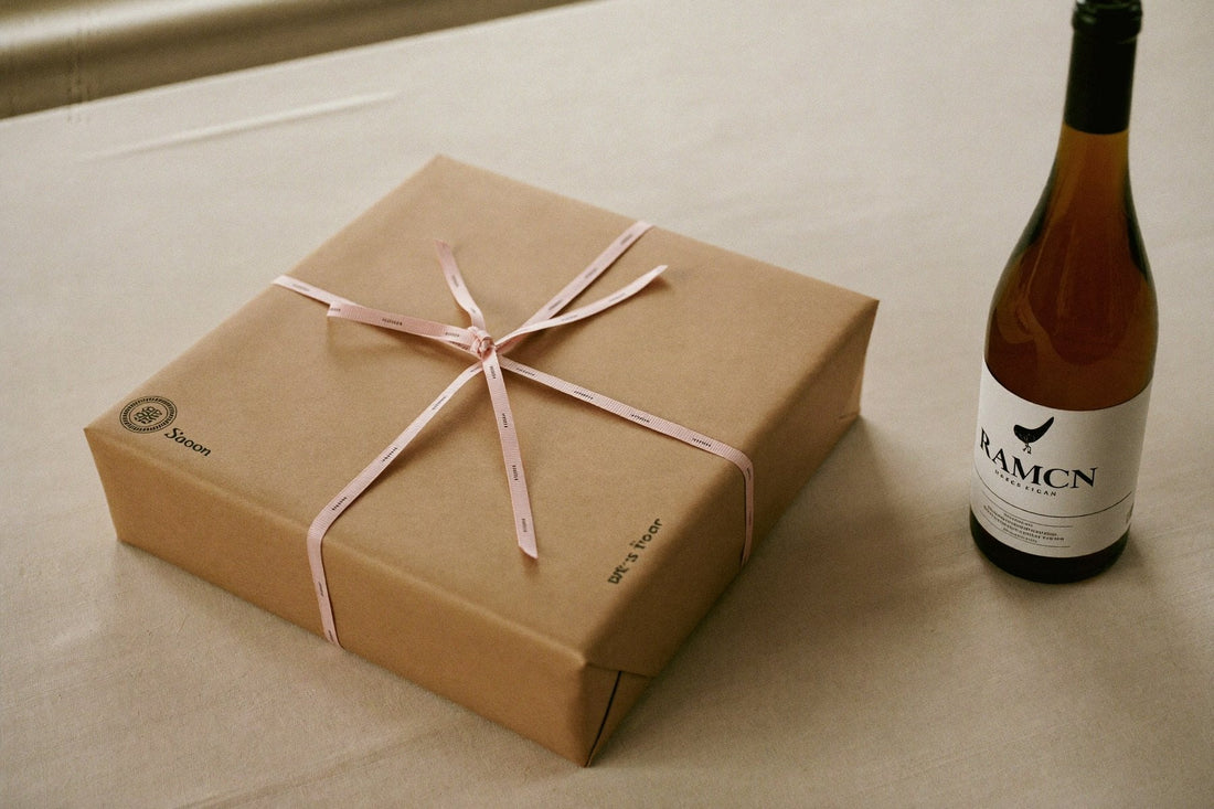 Wrapped gift with ribbon beside a bottle of white wine